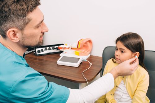 Young girl having left ear checked by audiologist