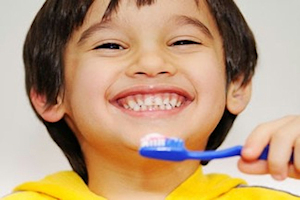 Boy smiling holding a blue tooth brush