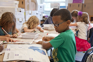 Boy in classroom wearing glassed and wearing green t-shirt