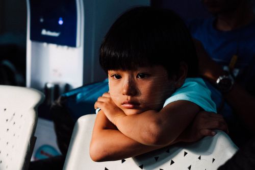 Sad child with head on folded arms