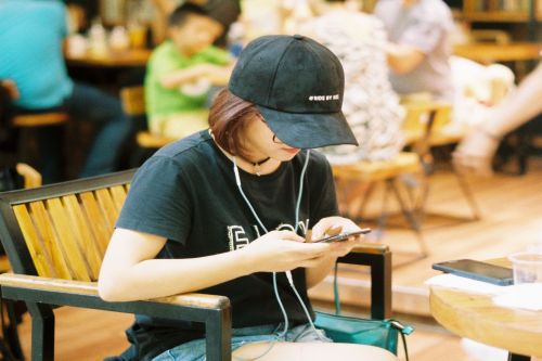 Girl wearing black cap and ear phones using smart phone