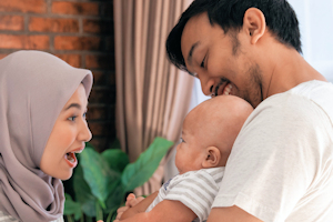 Smiling parents holding baby in stripy top