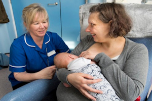Midwife with mother breastfeeding baby