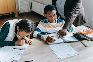 Young children sitting at a table writing in books