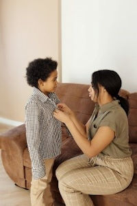 Woman buttoning shirt for child Woman buttoning shirt for child