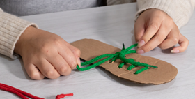 Child practising tying a green shoelace Child practising tying a green shoelace
