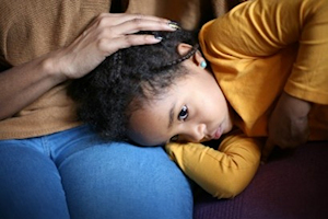 Young girl in yellow top resting head on lap