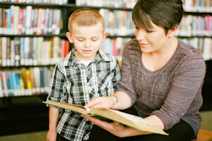 Woman reading a book to a young boy
