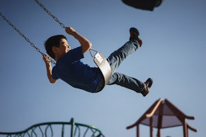 Young boy on swing blue sky in the background Young boy on swing blue sky in the background