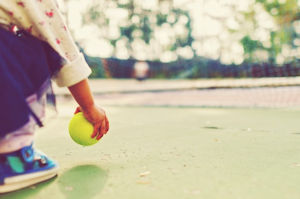 Child holding yellow ball in right hand