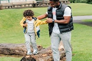 Adult supporting child walking on a log