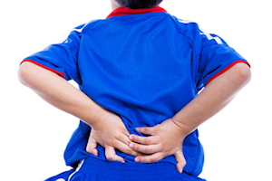 Boy wearing blue top with both hands on lower back