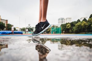 Person in black trainers jumping above a puddle