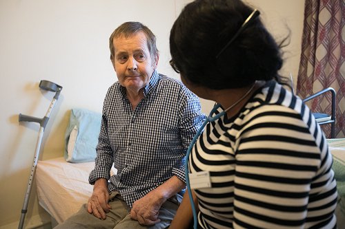 Female staff member in stripy top talking to a male patient