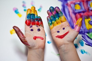Child with painted hands with happy and sad faces