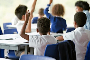 Children in classroom raising hands