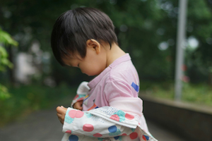 Child looking down wearing a coat with colooured spots
