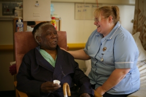 Smiling nurse with elderly male patient sitting in a chair