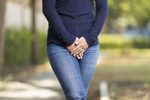 Woman crossing legs and cupping hands over pelvis