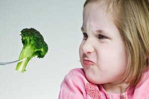 Girl grimacing at broccoli on a fork