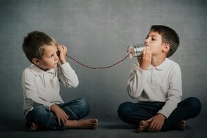 Boys talking and listening using tin cans and string