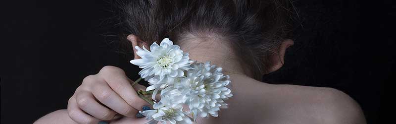 Women holding flowers over shoulder Women holding flowers over shoulder