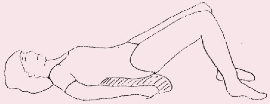 Picture of person in resting position - lying on their back with knees bent, and a cushion placed under the lower back