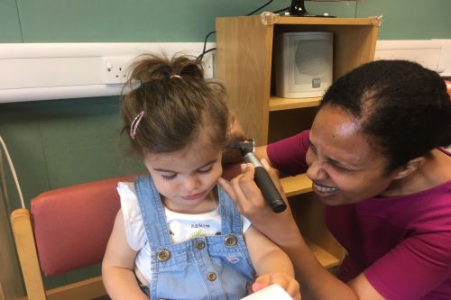 Young girl having left ear checked by audiologist Young girl having left ear checked by audiologist