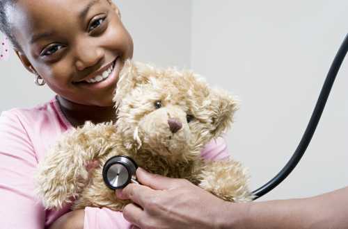 Young girl holding teddy bear with stethoscope on bear Young girl holding teddy bear with stethoscope on bear