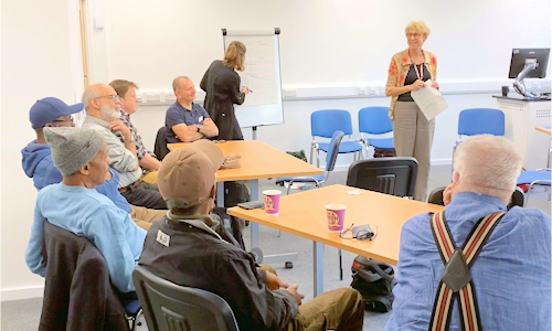 Patients sitting around tables in cancer support group Patients sitting around tables in cancer support group