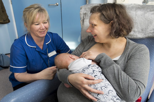 Mother breastfeeding baby in hospital chair