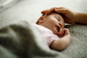 Adult hand on head of sleeping baby Adult hand on head of sleeping baby